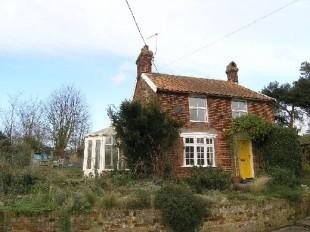 A brick house with a yellow door and white windows.