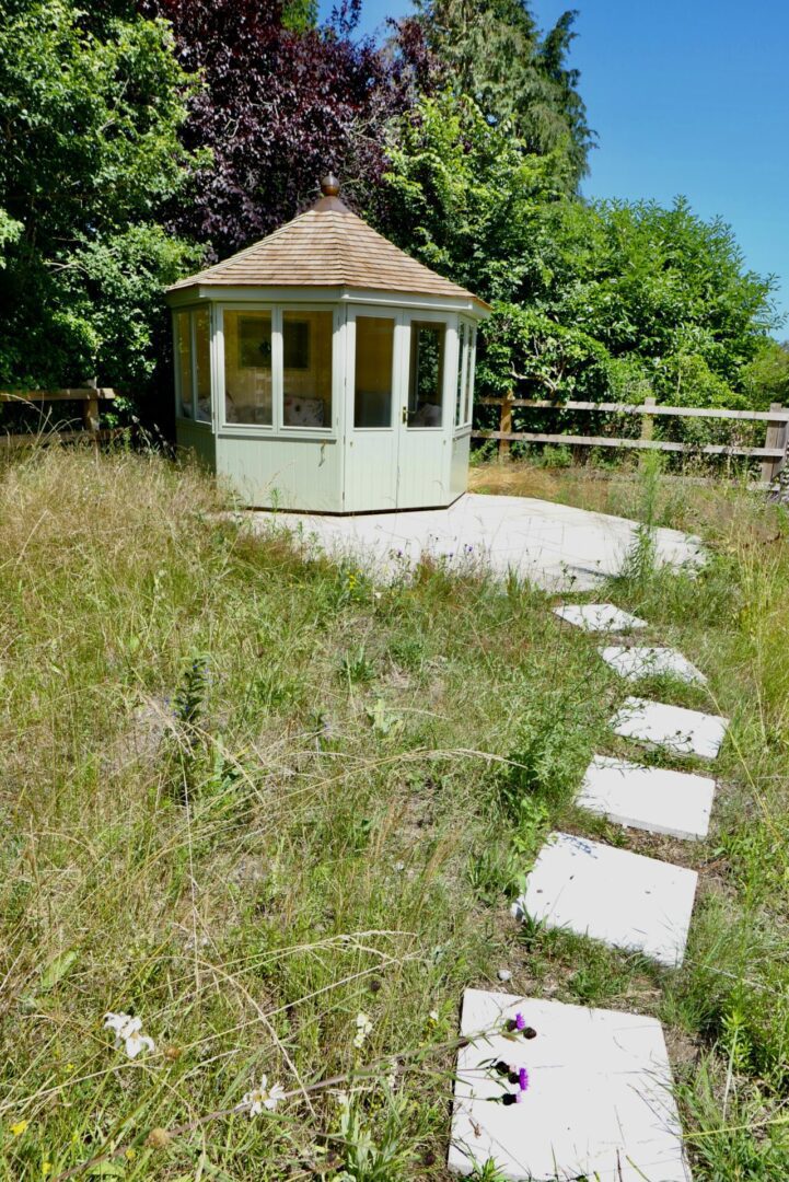 A gazebo with stepping stones in the grass.