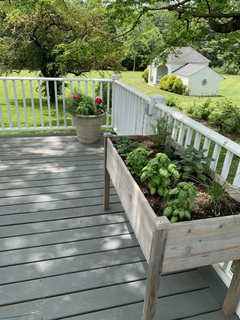 A wooden planter box with plants on top of it.