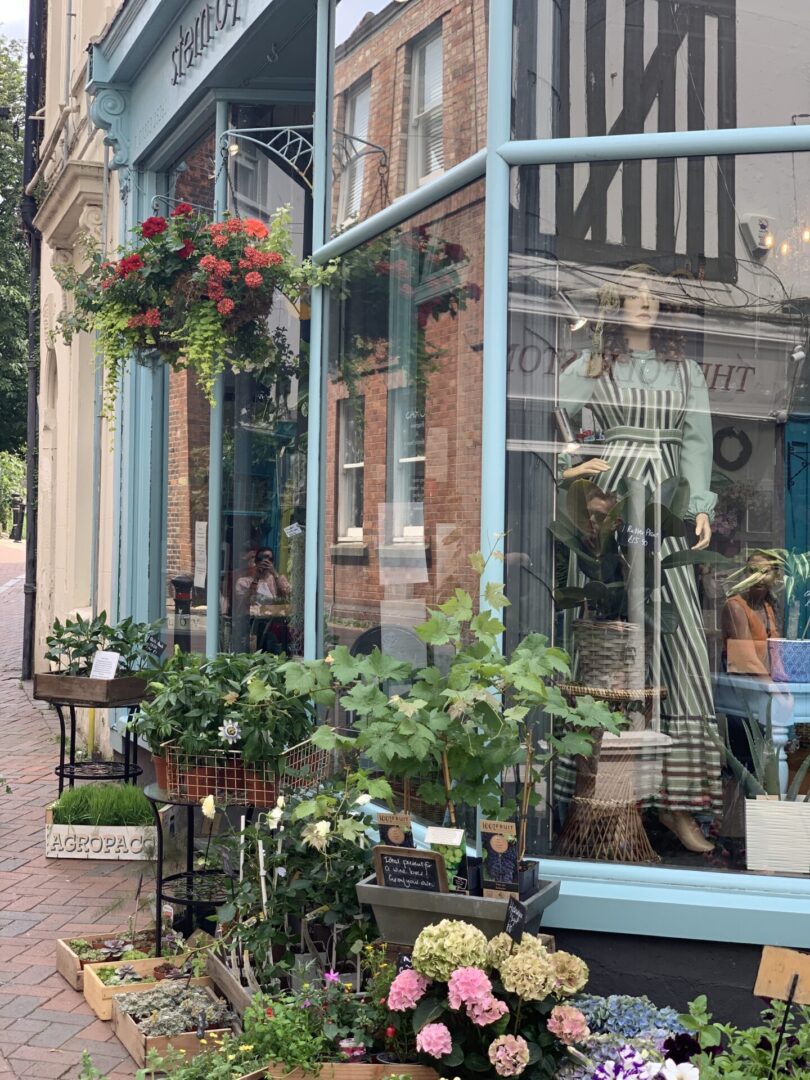 A store front with many plants on the outside.