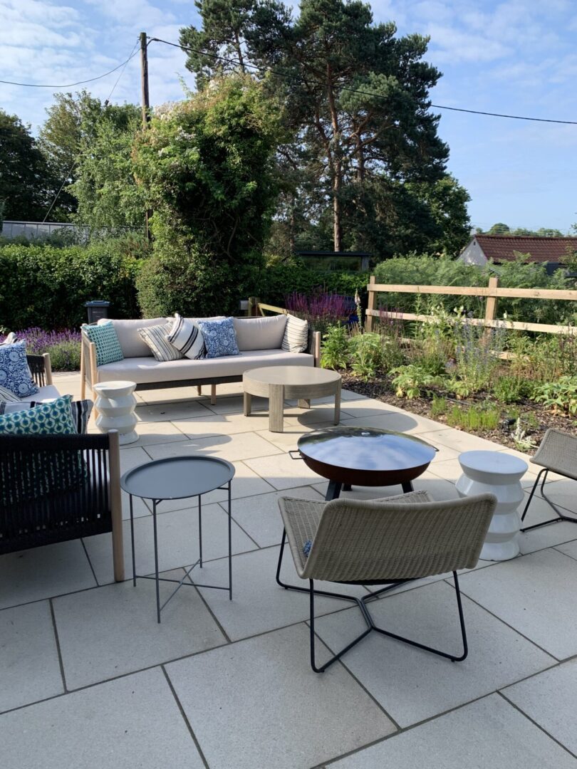 A patio with furniture and plants in the background.