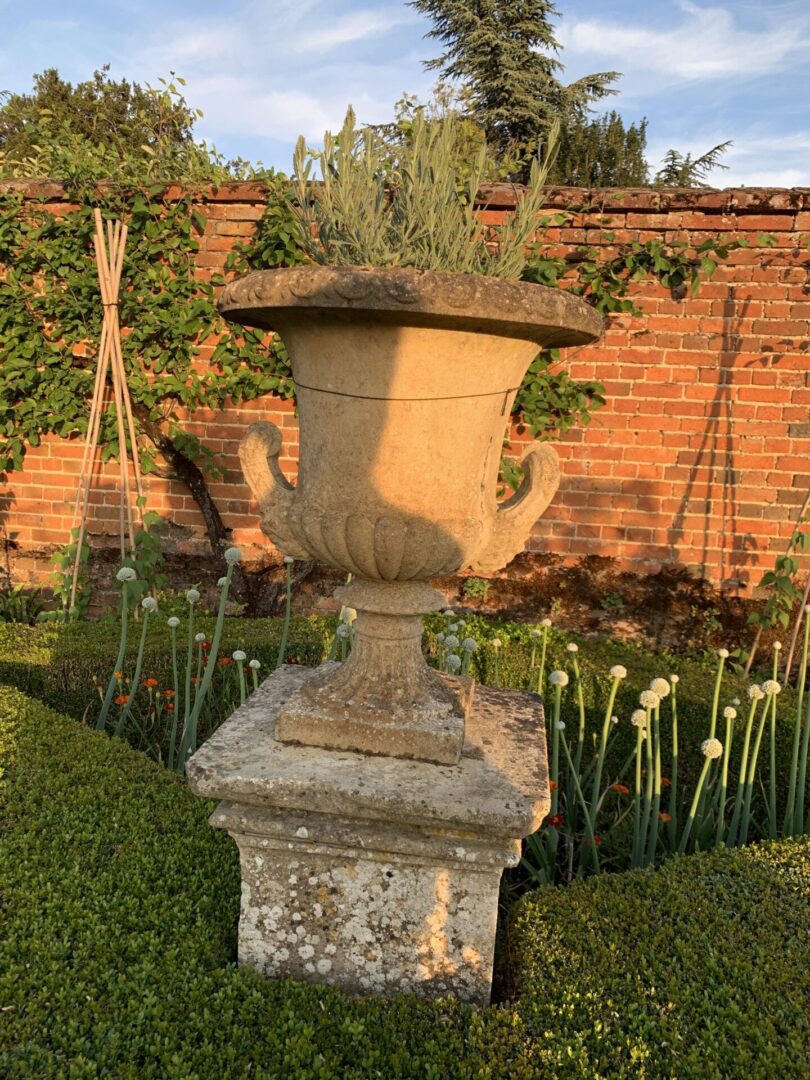 A stone urn sitting in the middle of a garden.