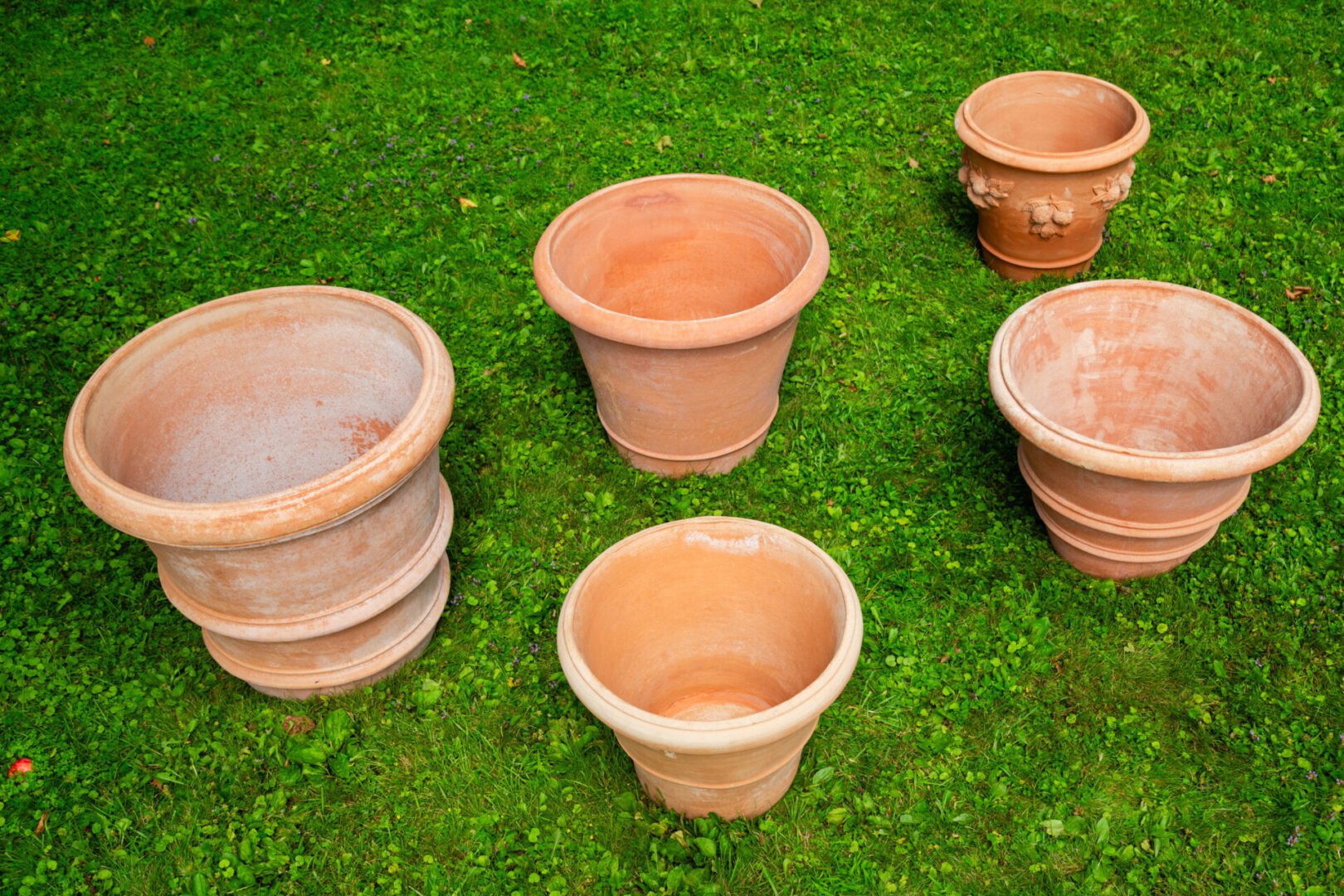 A group of five clay pots sitting on top of green grass.