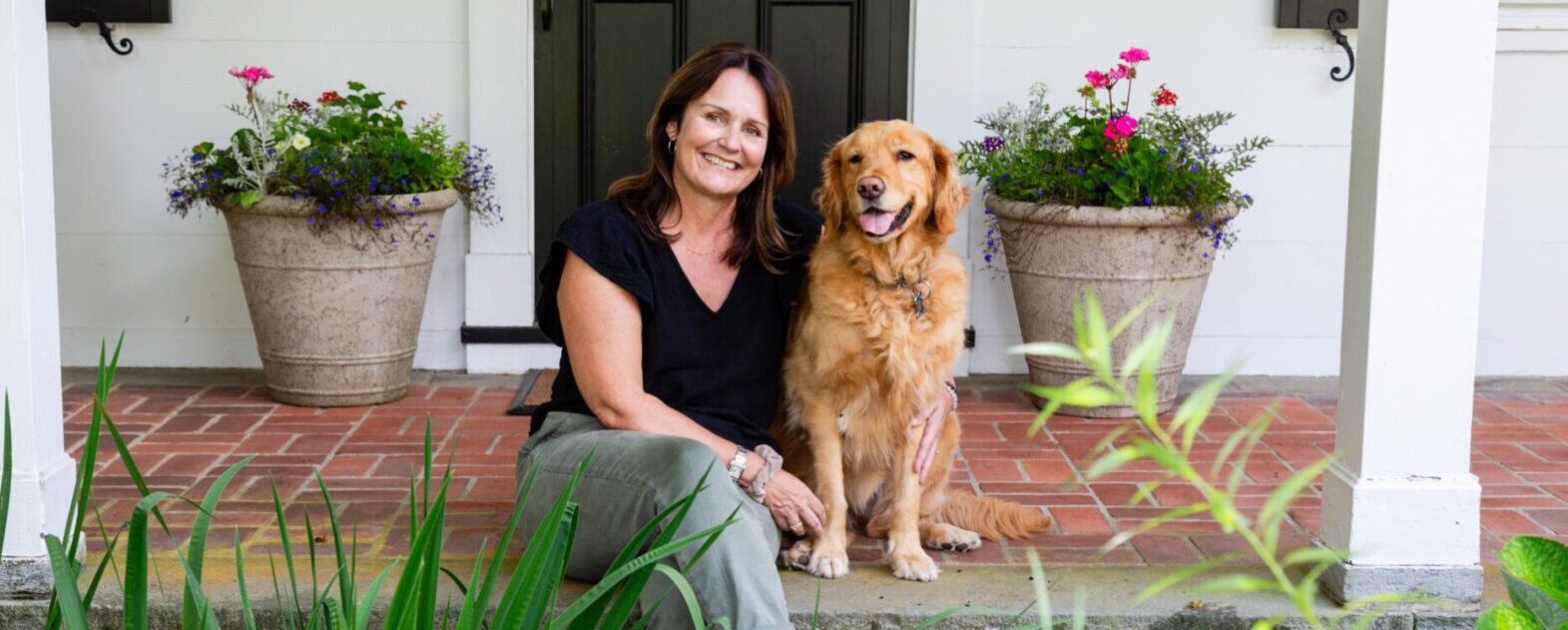 A woman sitting on the ground with her dog.