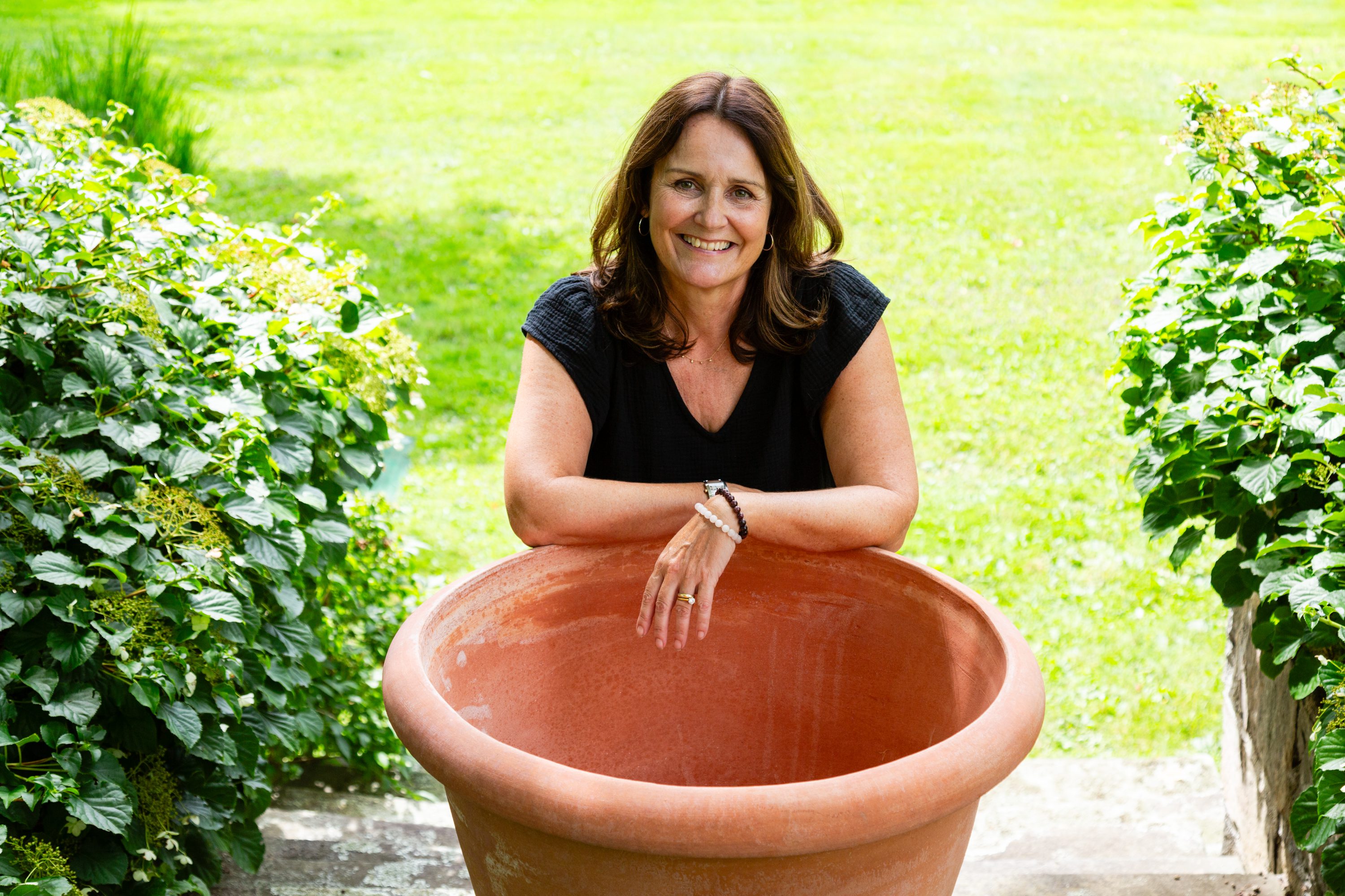 A woman sitting in a large flower pot.