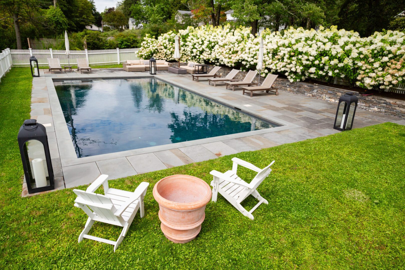 A lawn with two chairs and an empty pool