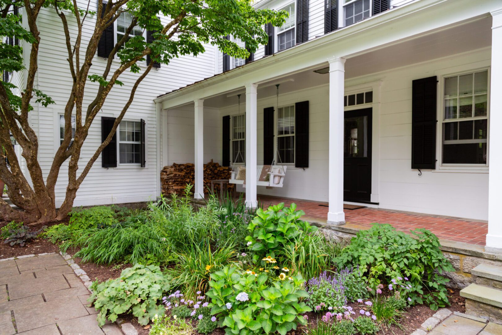 A white house with a garden in the front yard.