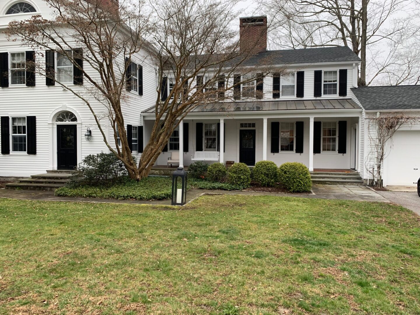 A white house with black shutters and a fire hydrant.