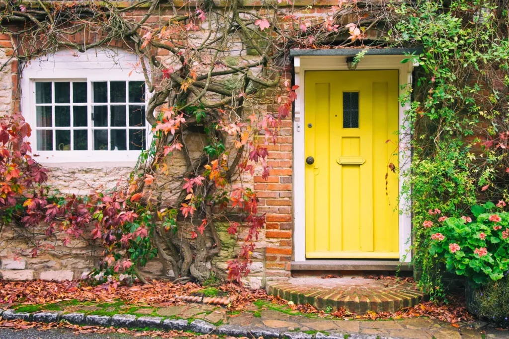 A yellow door and window on the side of a brick house.