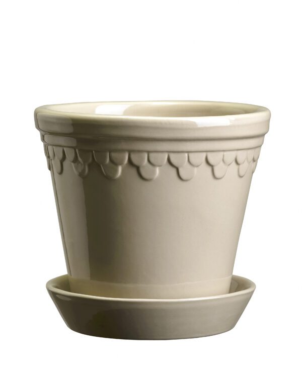 A white planter with a small saucer on top of it.