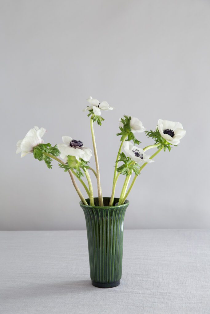 A green vase with white flowers in it