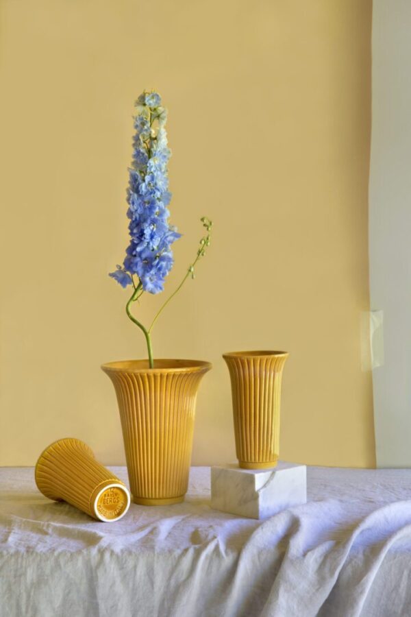 A yellow vase with flowers in it on top of some white blocks.