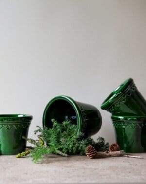 Green pots with greenery and pine cones.