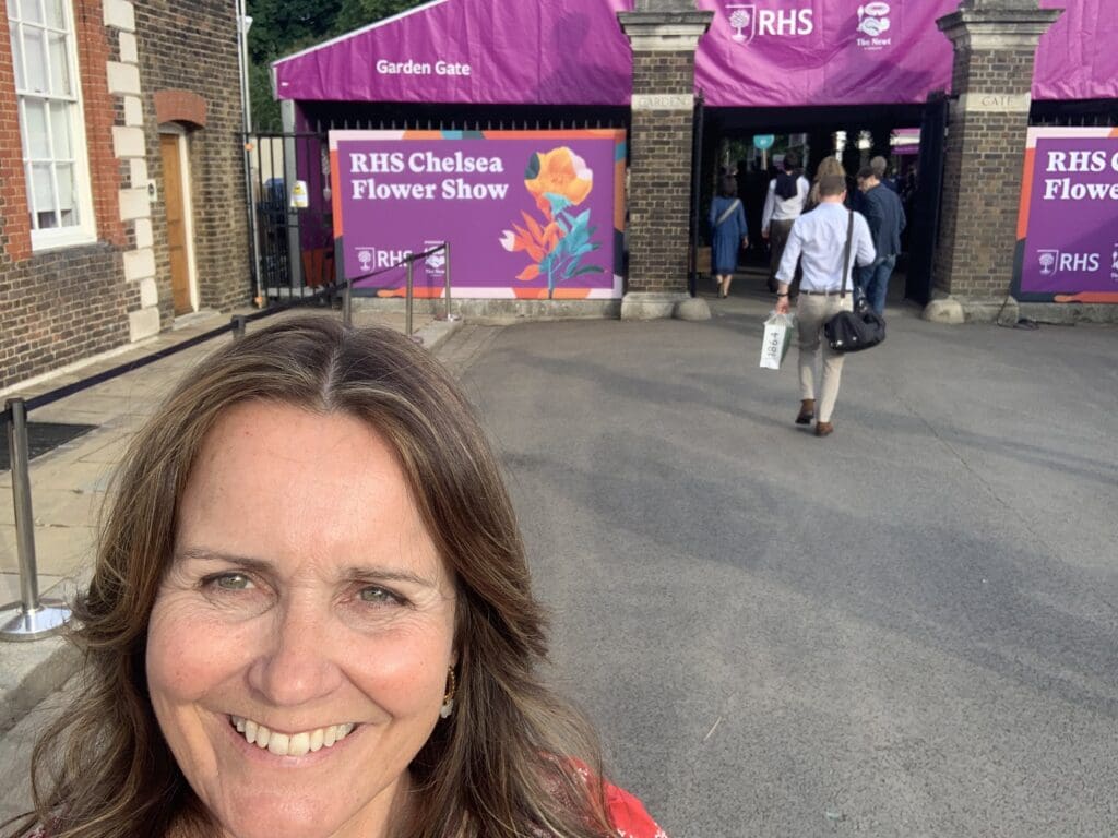 Woman smiling at Chelsea Flower Show entrance.