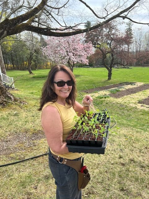 Woman holding seedlings in a garden.